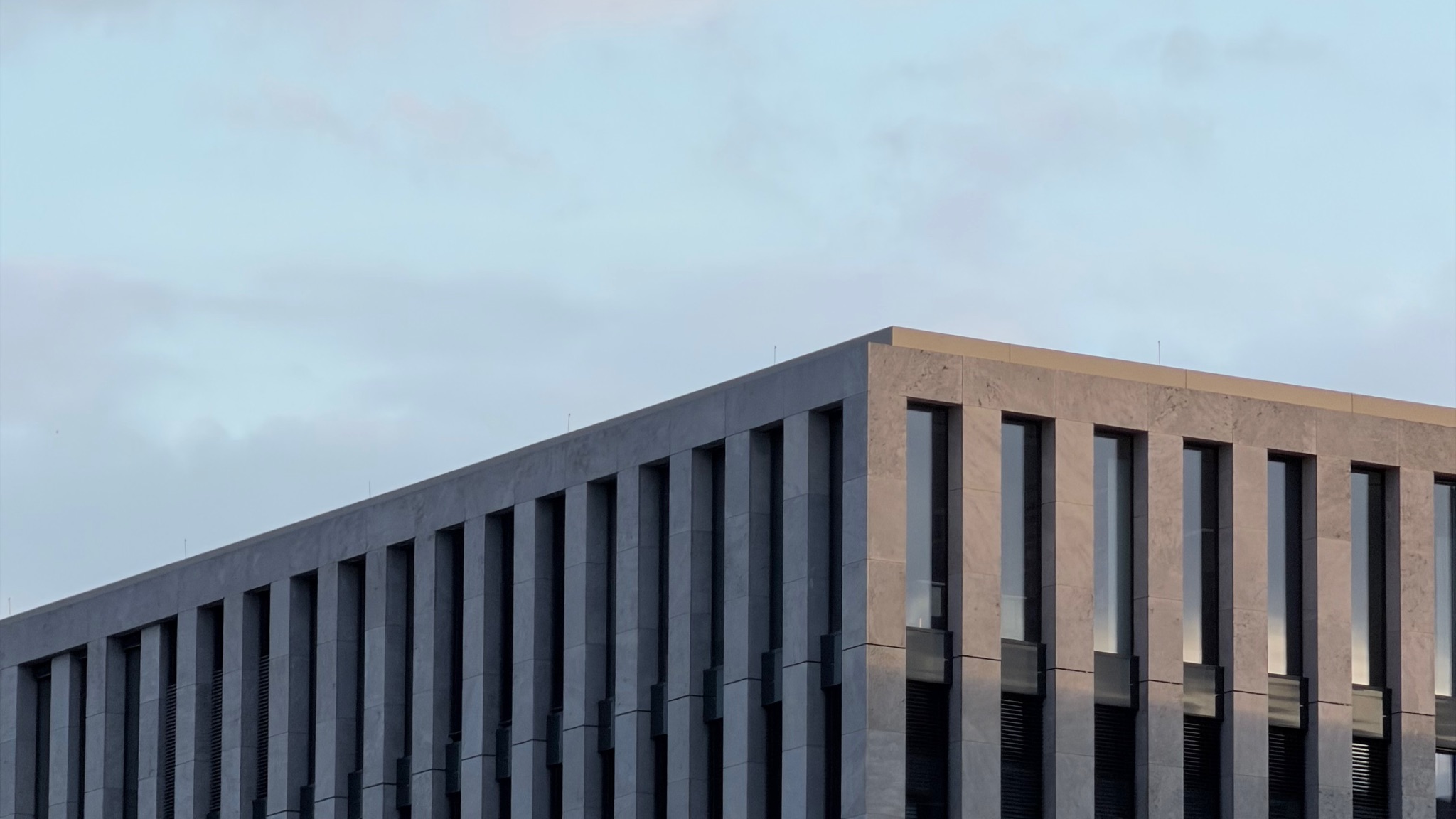 Concrete building with vertical windows against a cloudy sky